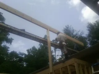 Carpenter setting a ridge beam over a new addition frame — Ice Dam Removal by Roofing Brothers in Padroni