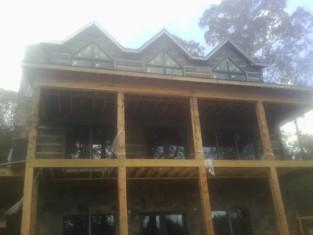 Dormers and porch framing on a large log home under construction — Roof Coating work by our crew in Padroni