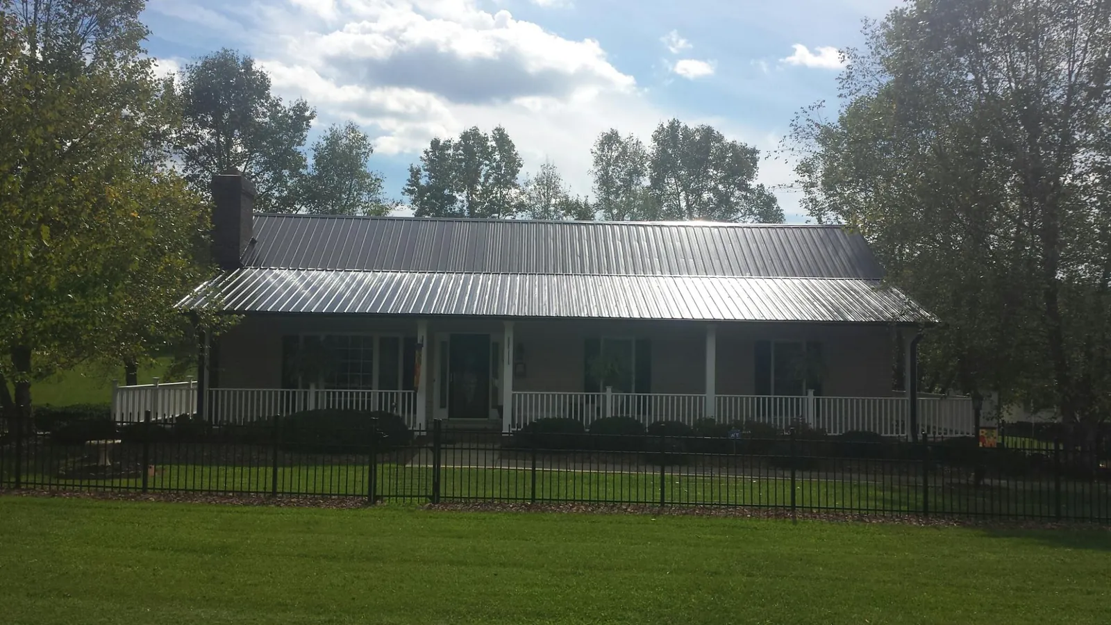 Gray metal roof on a brick ranch with a full width front porch — Gutter Guard Installation work by our crew in Padroni