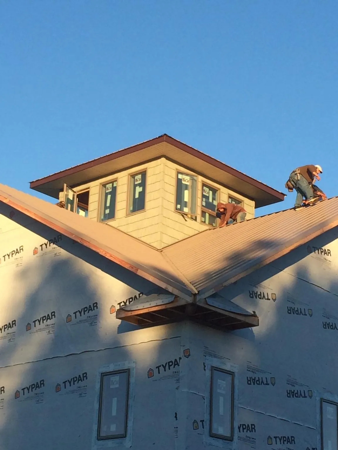 Roofers working around a rooftop cupola on a new metal roof at sunset — Roof Waterproofing in Padroni by Roofing Brothers